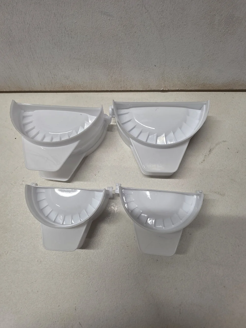 Set of 4 white plastic dumpling/empanada presses in two different sizes.